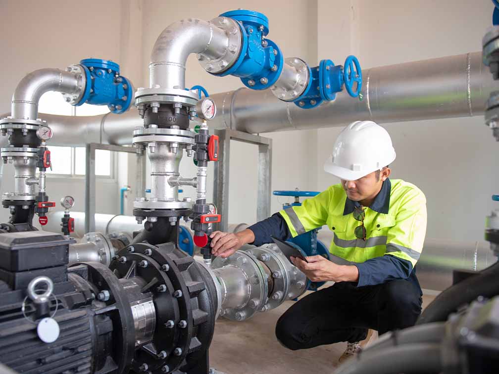 Engineer inspecting pipe connected to pump